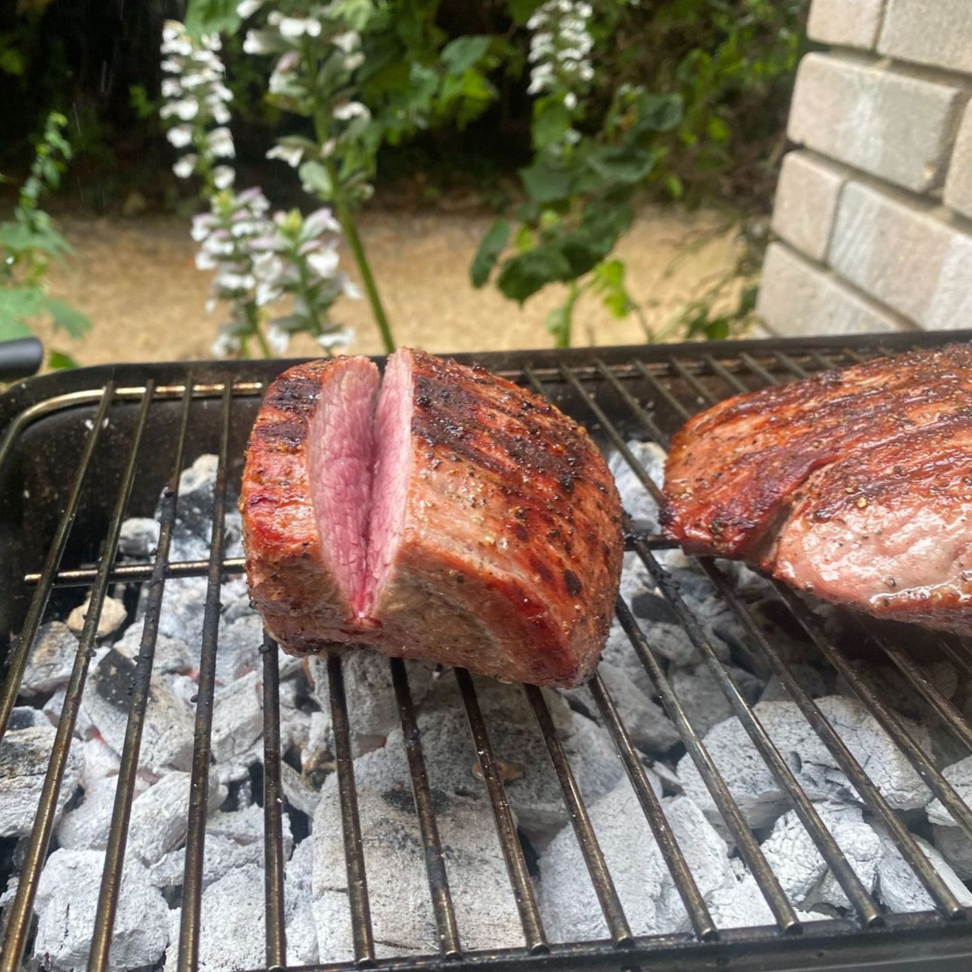 Weber BBQ cooking joint of beef on coals