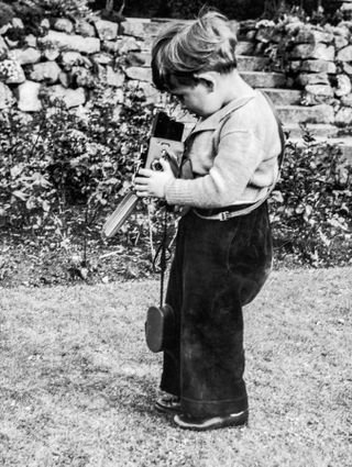 Prince Charles plays with a camera in the grounds of Balmoral Castle, Scotland, 28th September 1952.