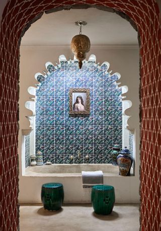 Red tiled archway, with white stone bath, green and blue splashback tiles