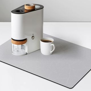 Gray coffee mat with a coffee maker and a cup of coffee on it