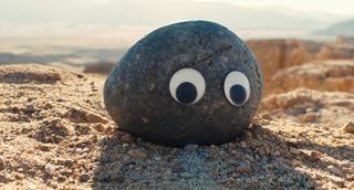 A rock with googly eyes on it sitting on a desert floor, from the film Everything Everywhere All At Once