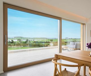 Expansive sliding aluminium-timber sliding door from Internorm door, installed in a modern new home, offering extensive views of the surrounding countryside and coast