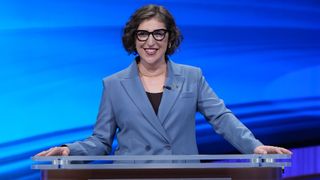 Mayim Bialik at the Jeopardy! podium in a blue suit