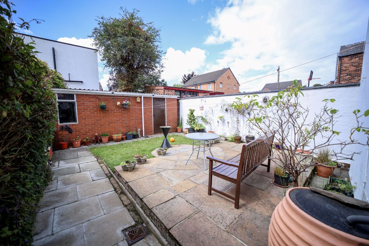 The rear garden shows a small lawn and a brick garage at the back