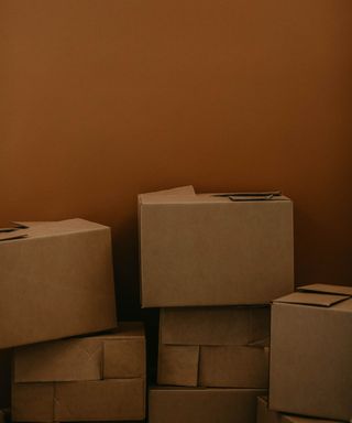 Brown cardboard moving boxes in front of a brown painted wall