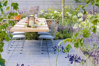 outdoor dining set in a small decked garden, with lots of plants and lavender planted on the boundaries