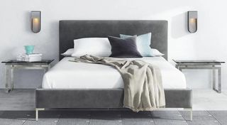 a bed with grey headboard, grey cushion and throw