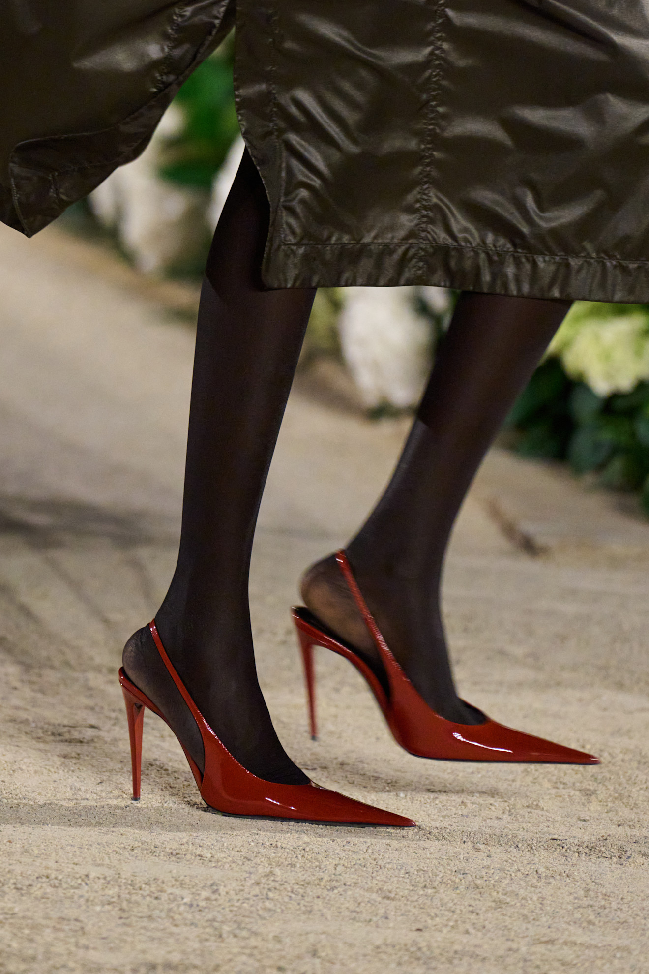 A Saint Laurent model at the S/S 26 show wearing burnt red slingback pumps.