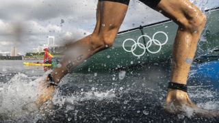 A pair of legs emerging from the water during the trathlon in the 2020 Olympics.