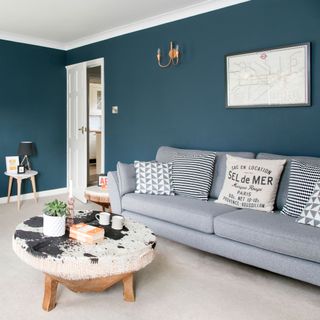 Deep blue living room with light grey carpet and a smart grey sofa