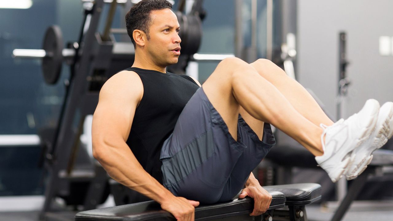 A man performing &#039;in out&#039; crunches on a weight bench