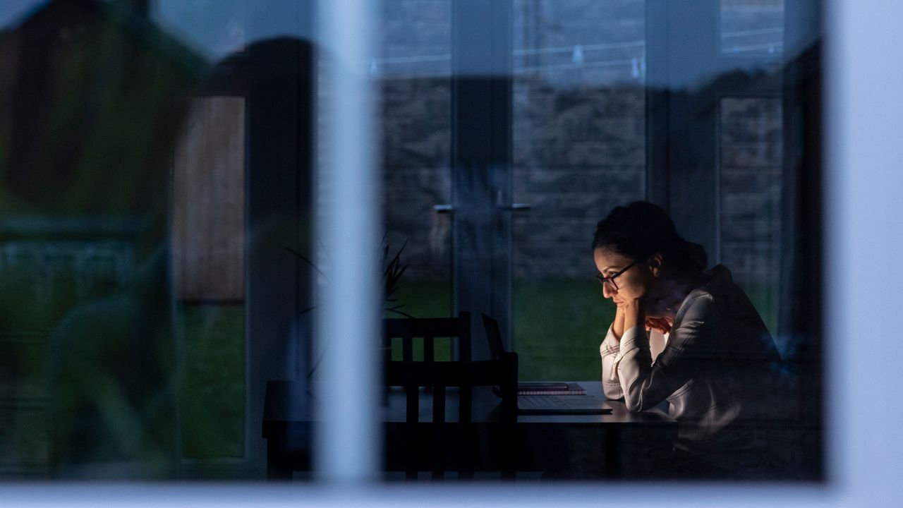 Woman sits inside as it is dark outside 