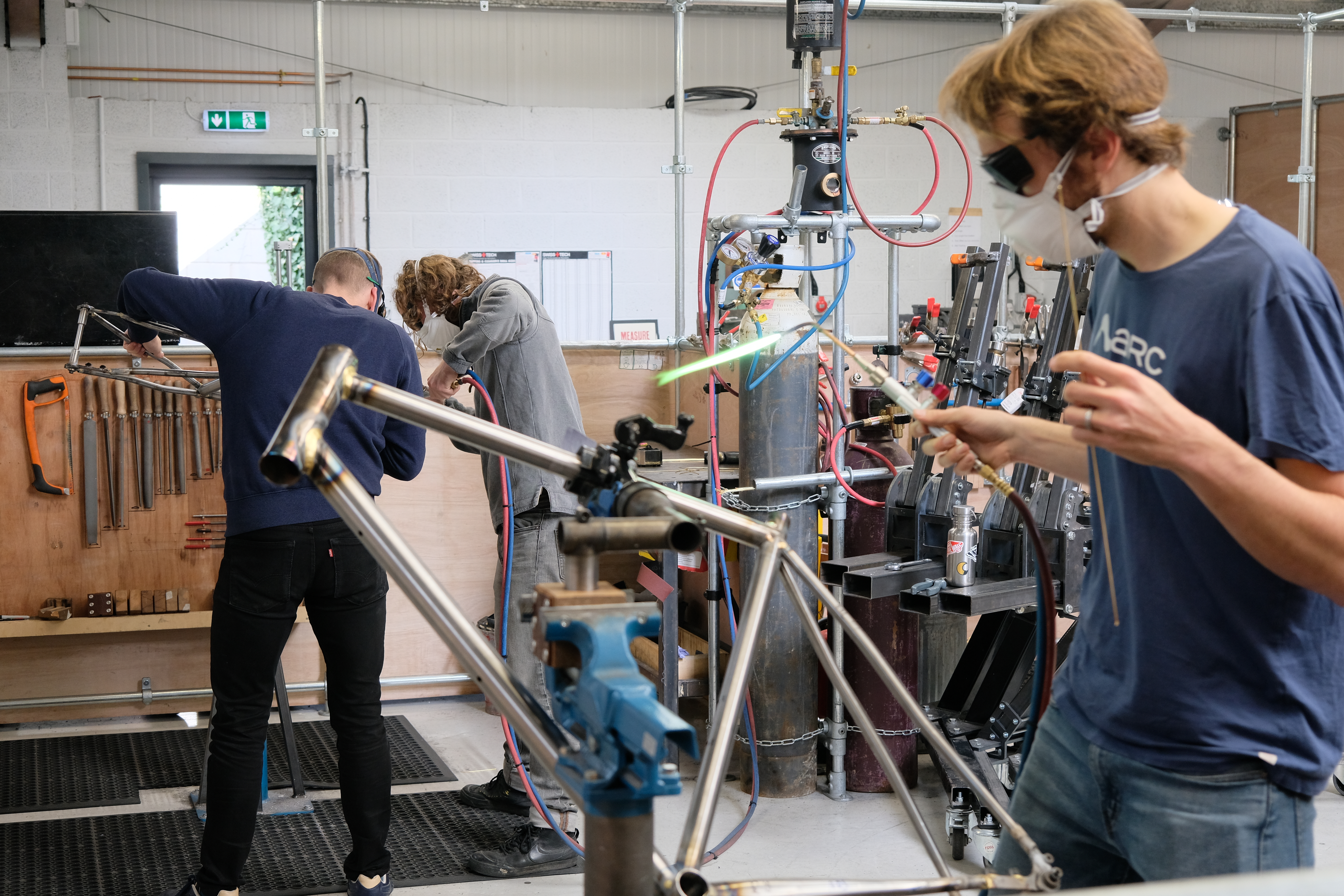 Three men work on building separate bike frames