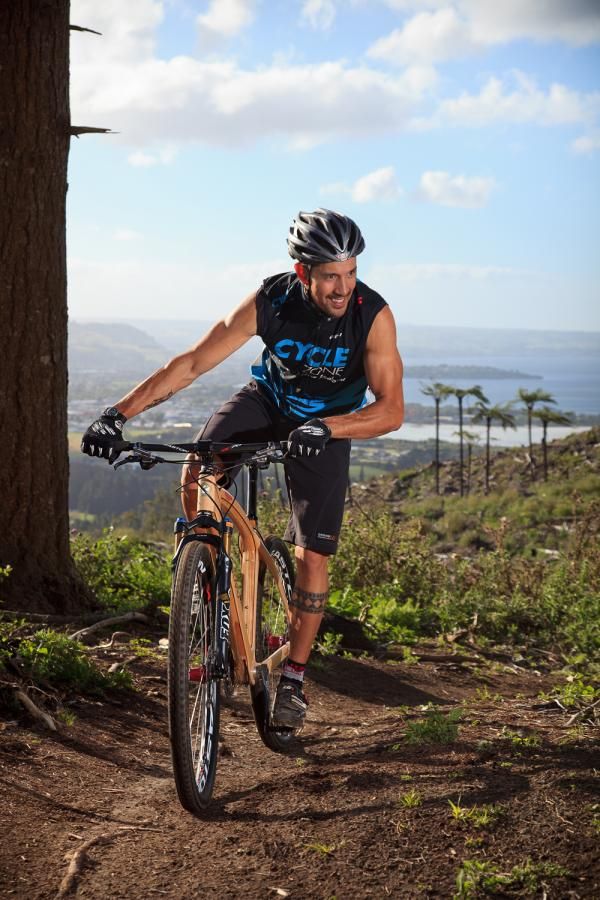 Marcello rider crests a hill on Gunna Gotta trail with Lake Rotorua and Rotorua city in the background. Bike is the Renovo Red Stag 29er, built from NZ Pine