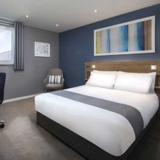 Photo of 'SuperRooms' from the Travelodge with white hotel bed, blue wall, grey carpet