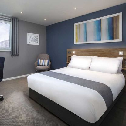 Photo of 'SuperRooms' from the Travelodge with white hotel bed, blue wall, grey carpet