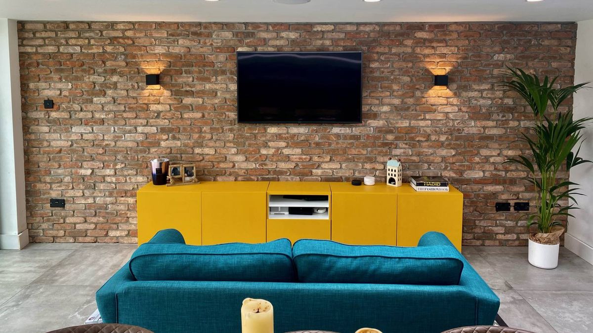 brick living room with black wall lights and blue sofa