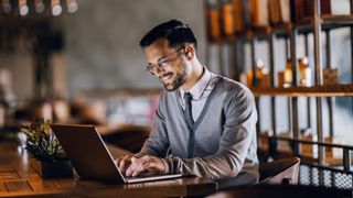 A man sitting as a desk and using a laptop