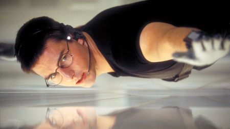 Mission Impossible movies in order: Tom Cruise as Ethan Hunt hanging from a wire during the first Mission Impossible movie. 