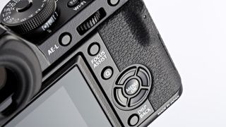 Close-up of rear of black Fujifilm X-T1 on a white background, with part of the rear LCD and viewfinder showing, along with the thumb grip and various physical buttons