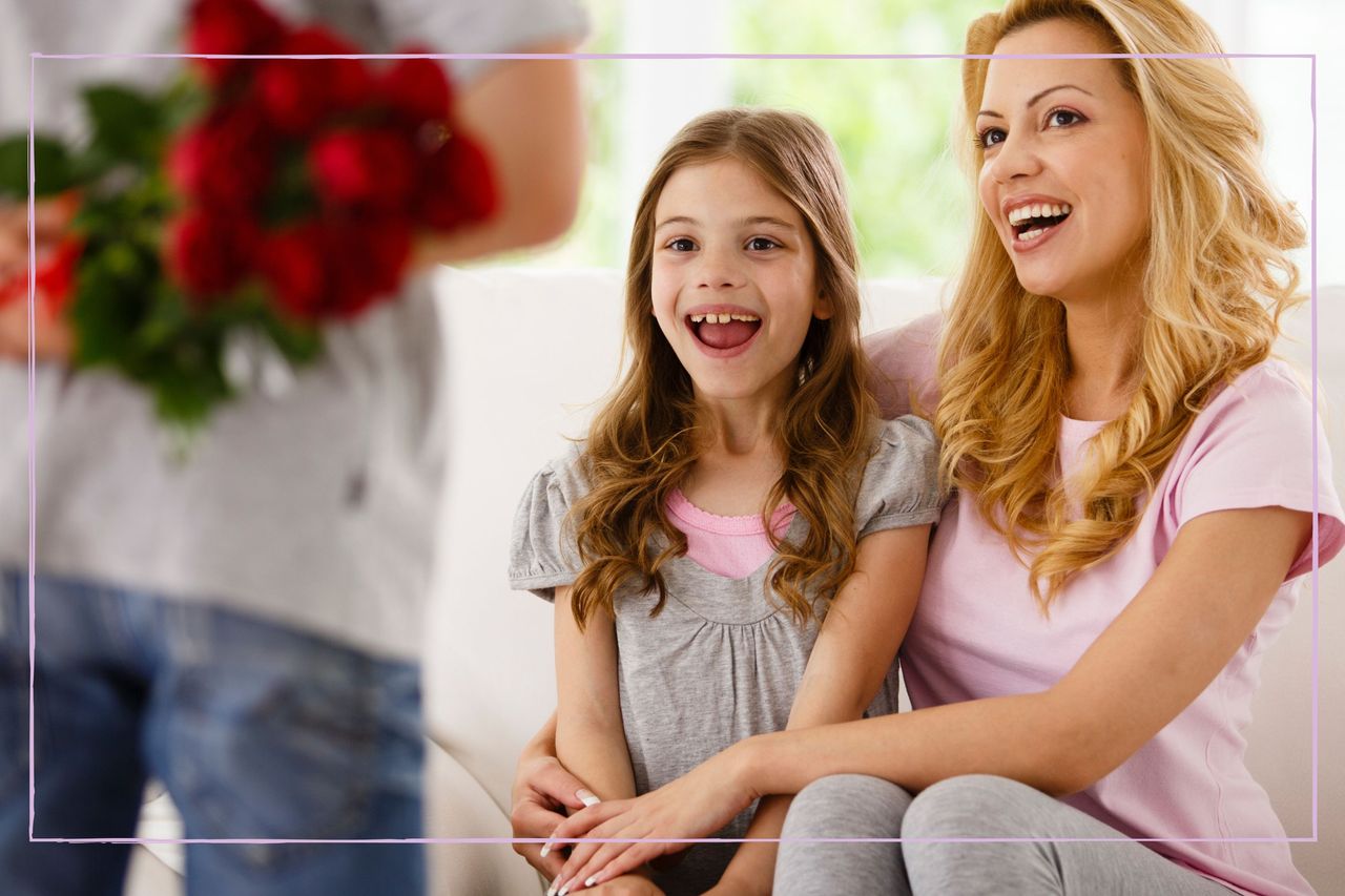 Mum and daughter sat on sofa with boy in front holding red roses behind his back