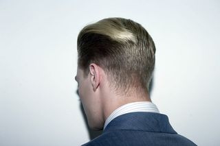 back of male models head wearing blue suit, blonde hair smoothed back