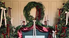 a christmas fireplace with the wreath connecting to the garlands in a dramatic swoop