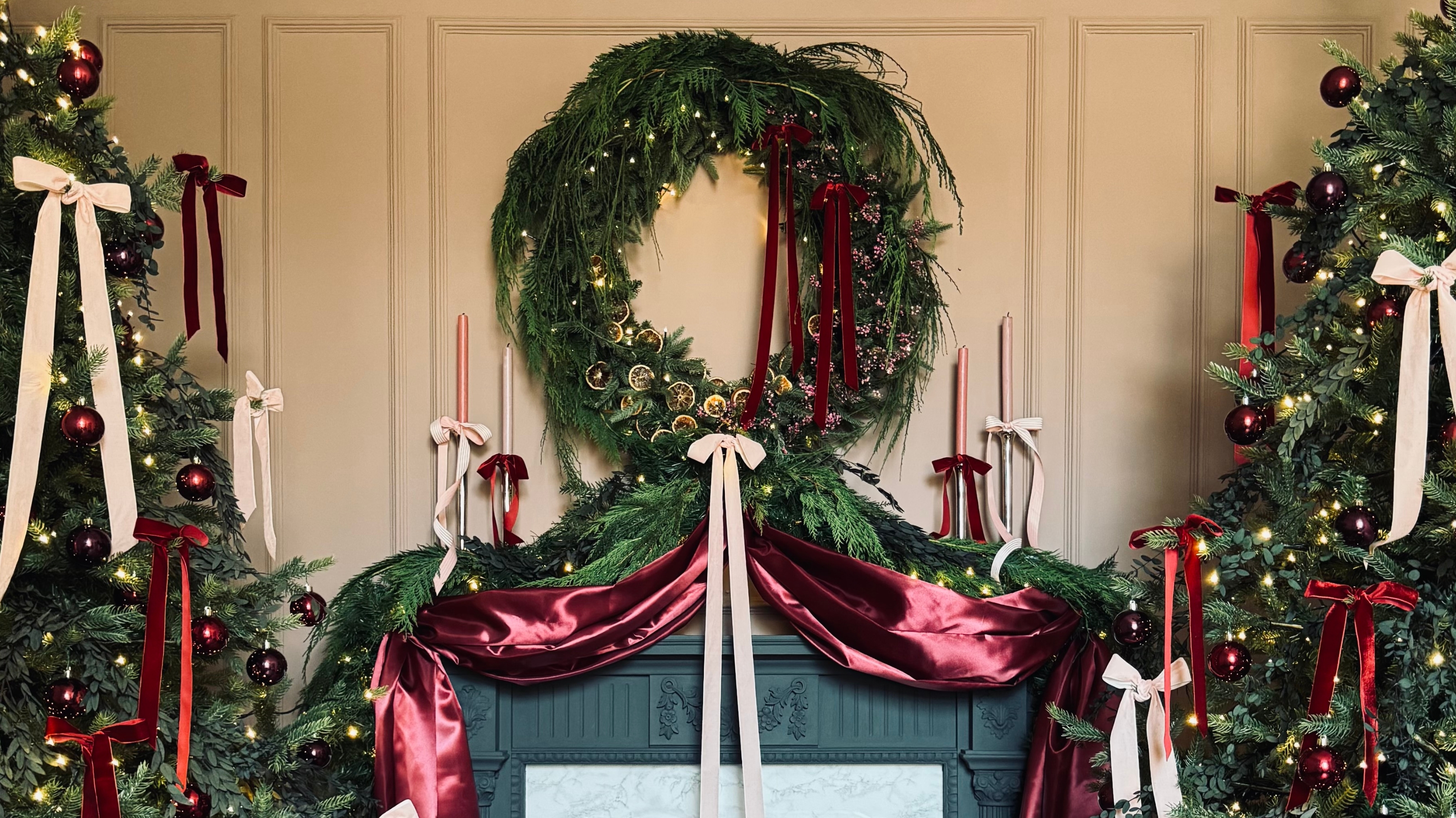 a christmas fireplace with the wreath connecting to the garlands in a dramatic swoop