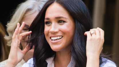Meghan Markle pushes her hair away from her face