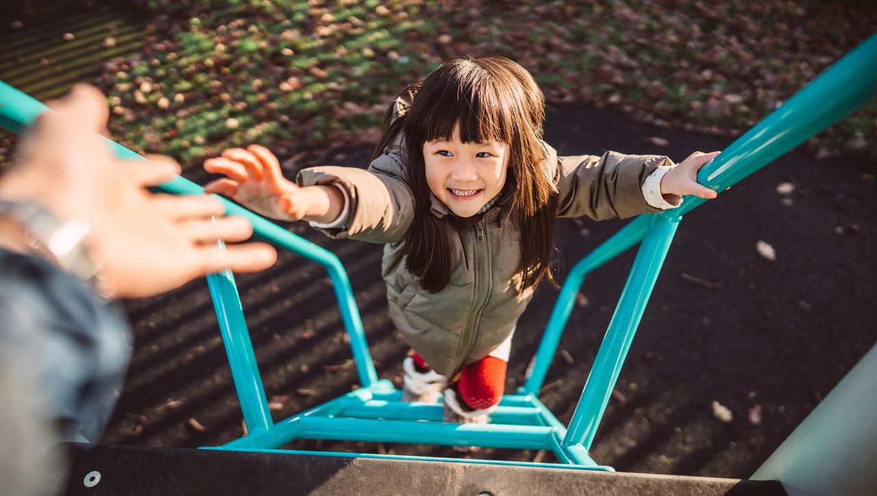 Little girl climbing the steps of a slide in a playground.