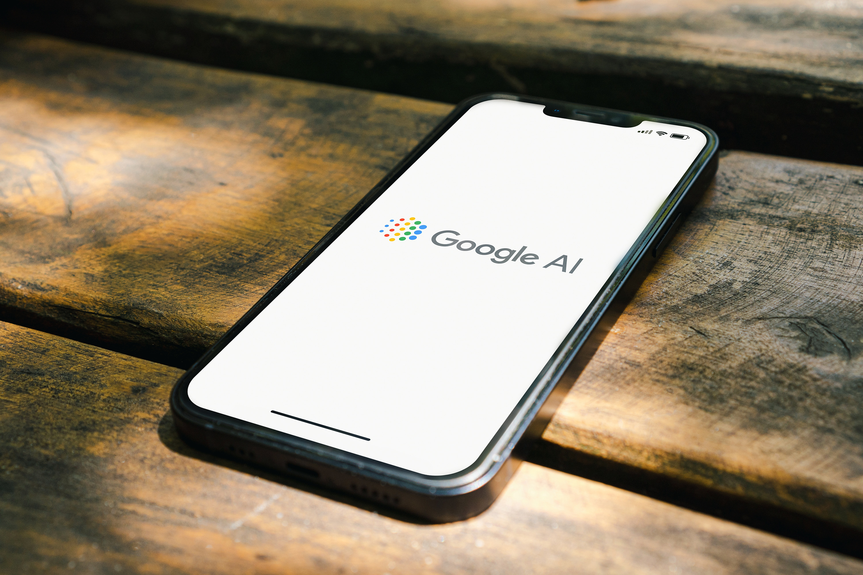 Google AI-Logo auf einem Telefon, das auf einem Tisch liegt