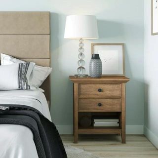 A simple wooden nightstand in a blue, white and neutral bedroom