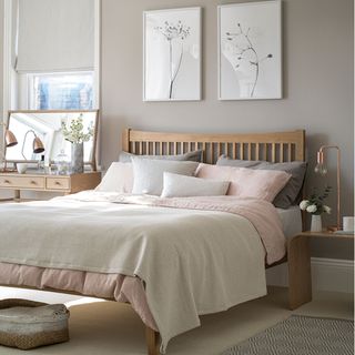 Neutral bedroom with artwork, wooden bed and dressing table