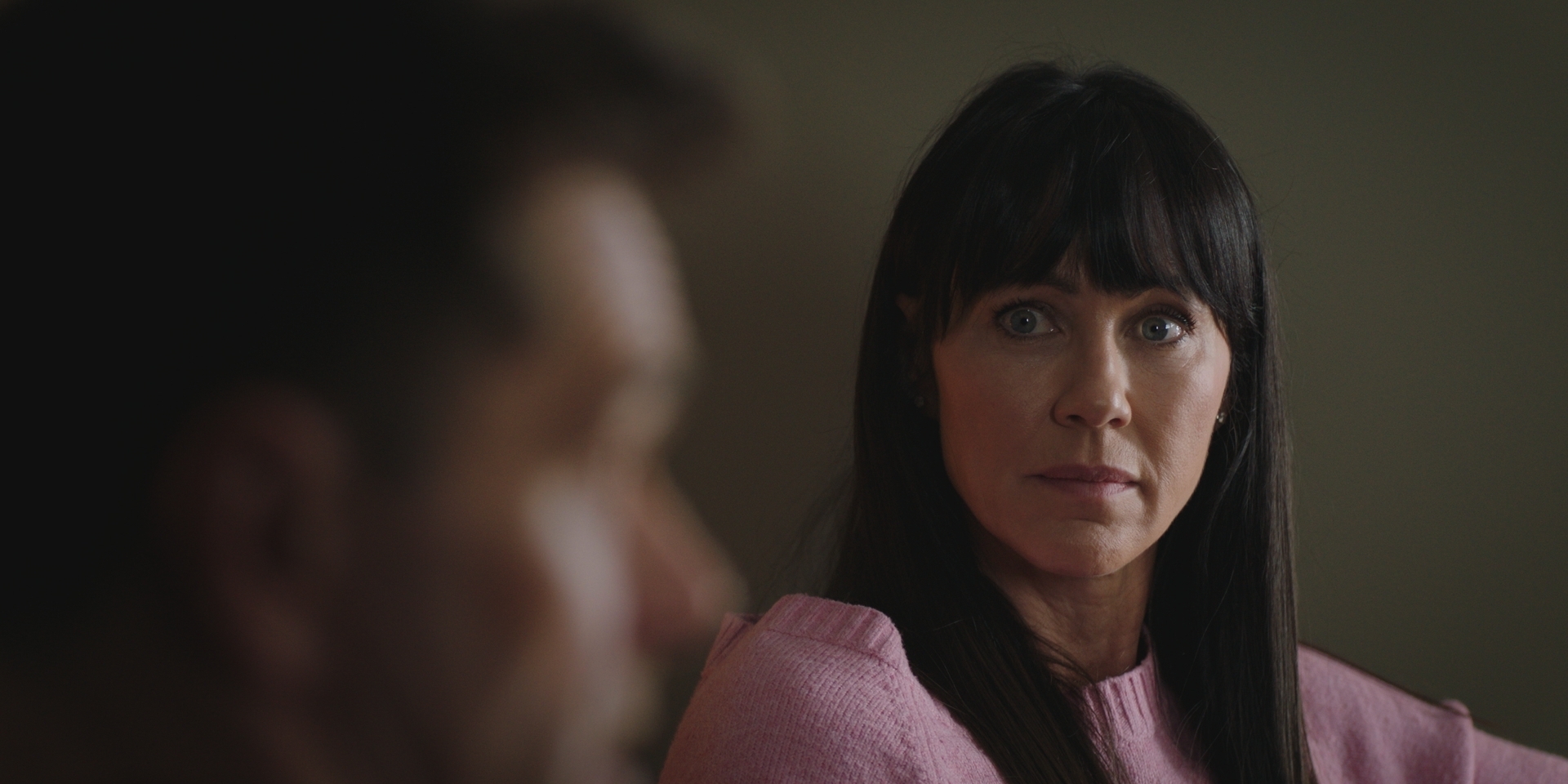 Faith wearing a pink jumper, looks at Iain with concern when they attend their first couple's therapy session.