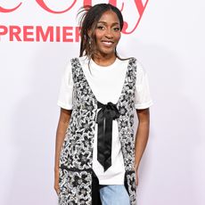 Ayo wears a white tee, black and white top, and jeans