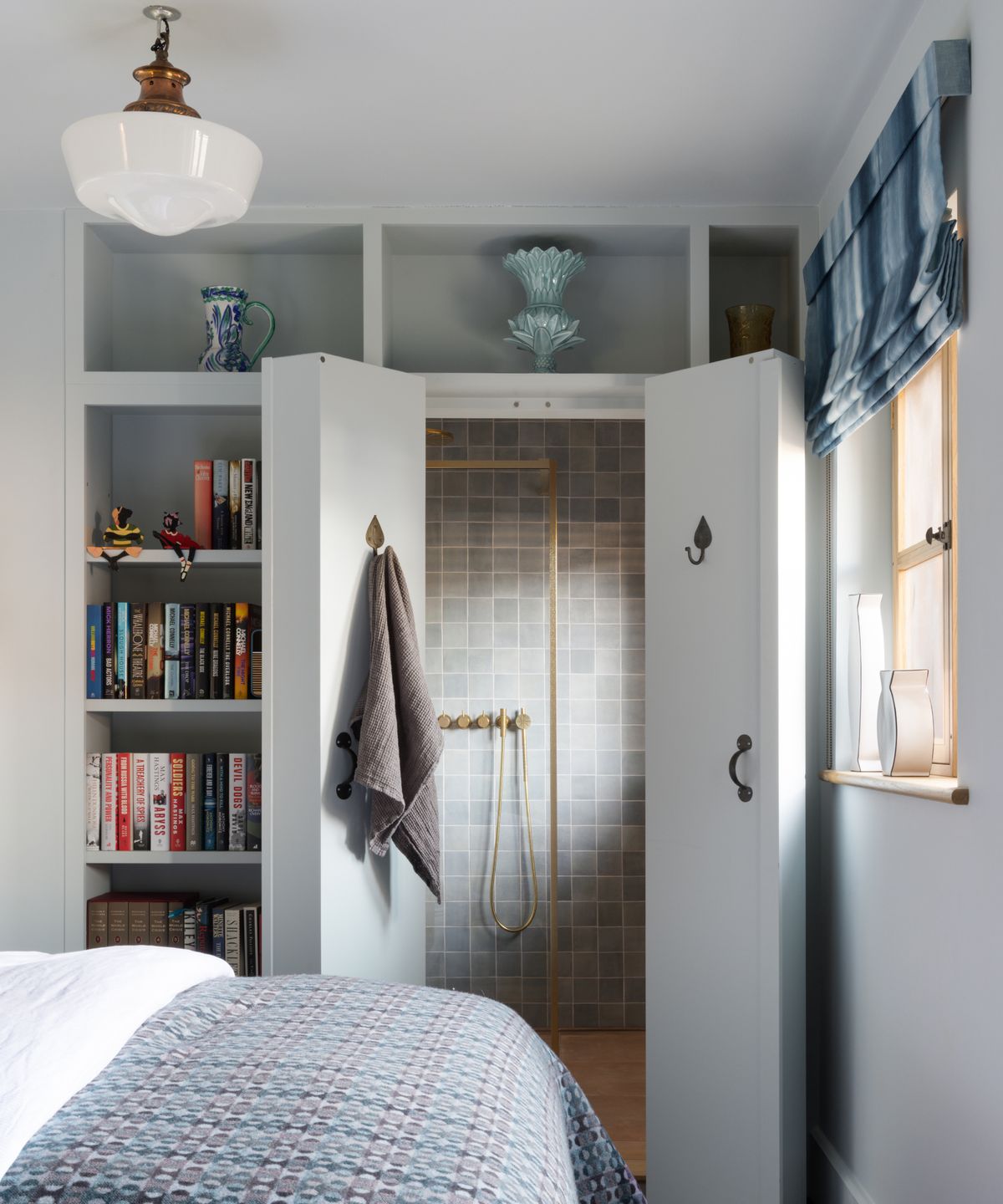 built in pale grey painted book shelving unit in bedroom concealing doors which open onto ensuite