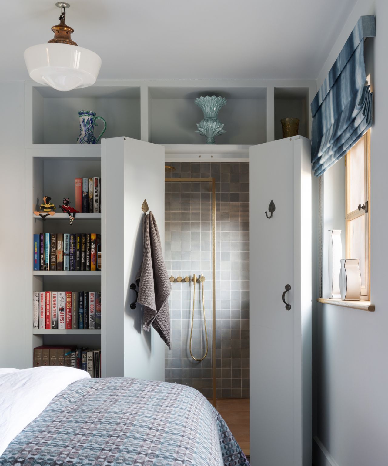 built in pale grey painted book shelving unit in bedroom concealing doors which open onto ensuite