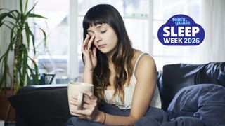 Tired woman rubbing her eyes holding a coffee cup