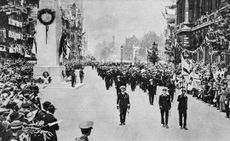 P8JD89 A military march past at the Cenotaph War memorial unveiled by King George V on 11 November 1920, the second anniversary of the Armistice with Germany which ended the First World War. The unveiling ceremony was part of a larger procession bringing the Unknown Warrior to be laid to rest in his tomb nearby in Westminster Abbey. The funeral procession route passed the Cenotaph, designed by Edwin Lutyens, where the waiting King laid a wreath on the Unknown Warrior's gun-carriage before proceeding to unveil the memorial which was draped in large Union.