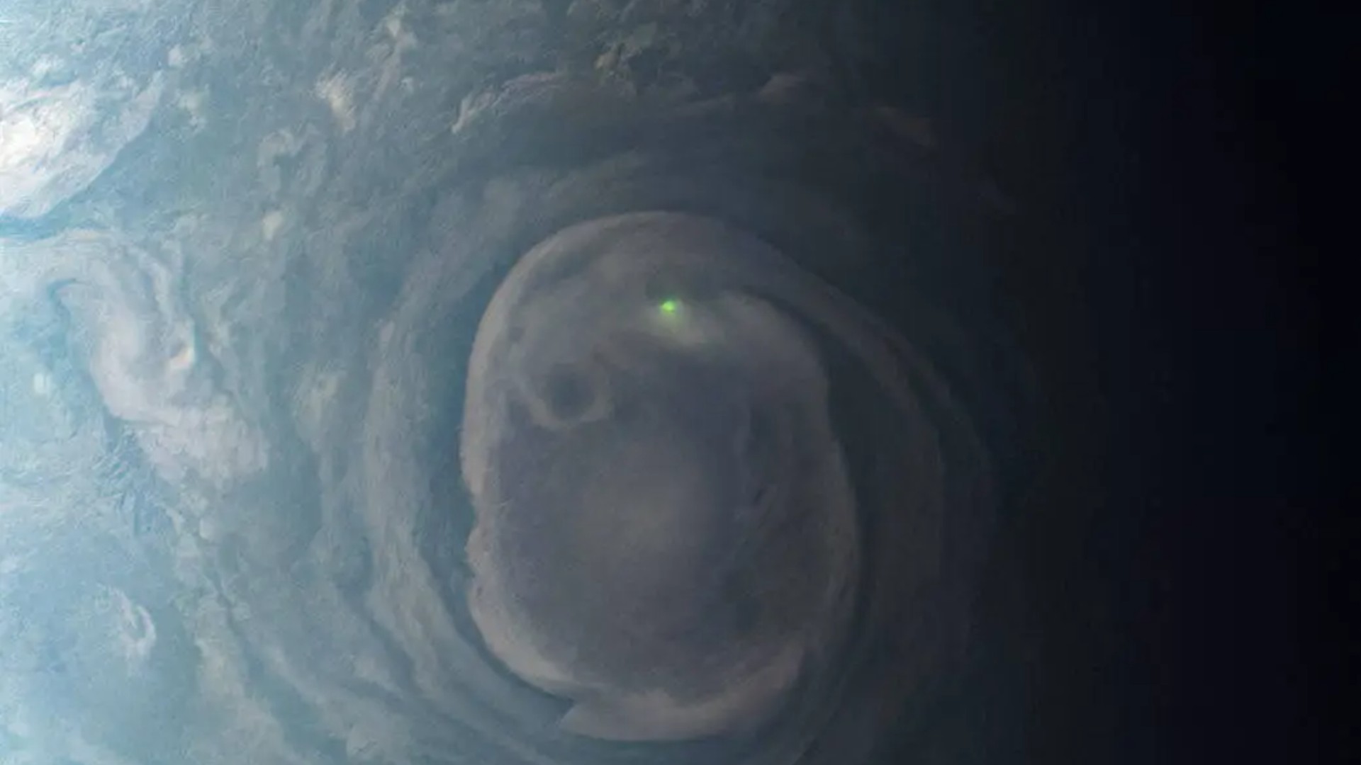 a bright dot of light in the center of a green and grey swirl