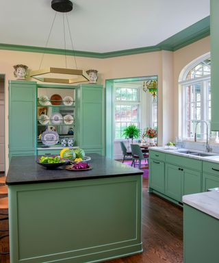 kitchen with pale green cabinets and granite worktops and island