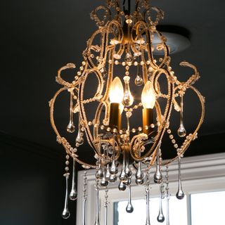 A black-painted ceiling with an ornamental switched-on chandelier