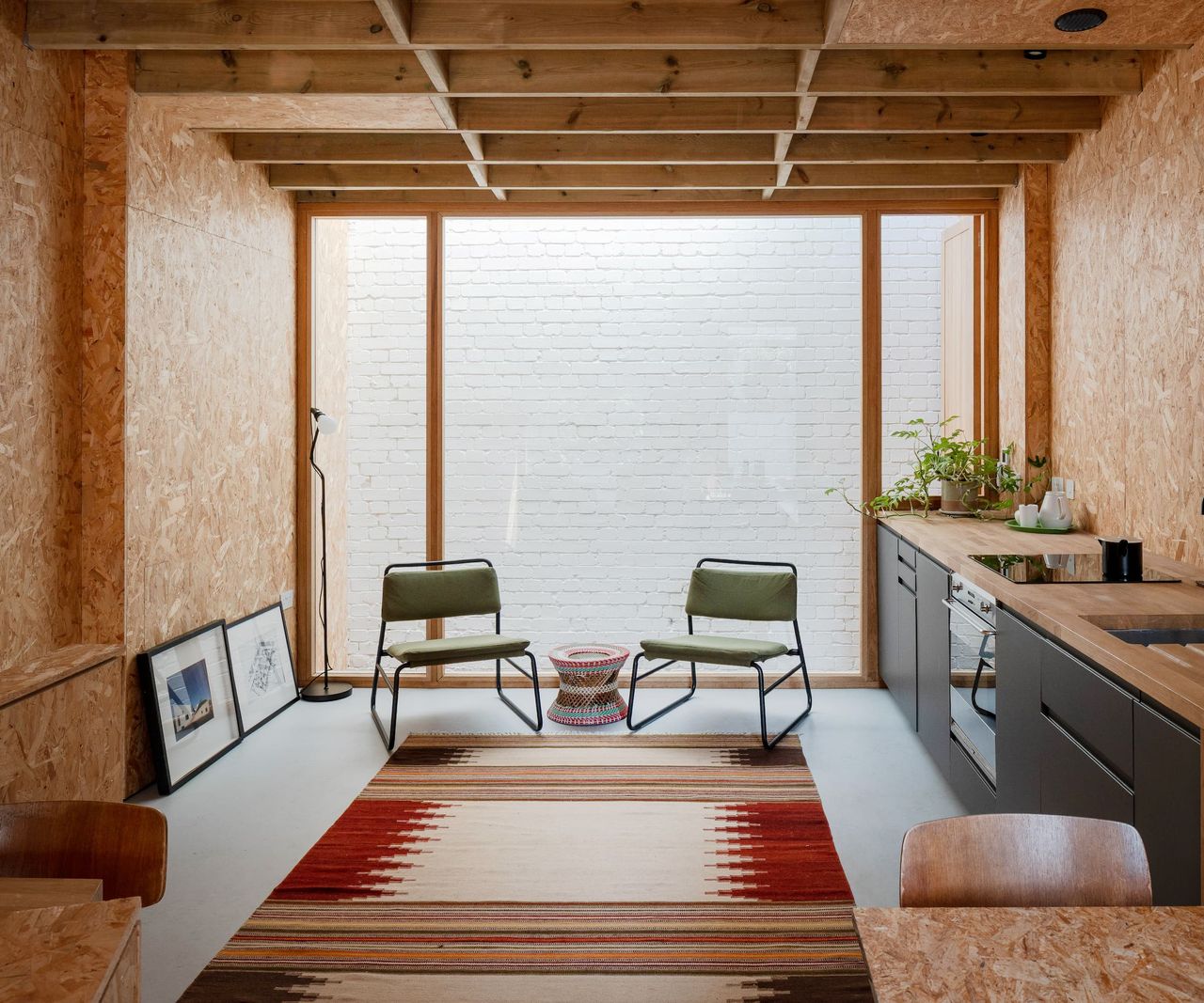 A kitchen-diner with plasterboard walls and a carpet on a cement layed floor