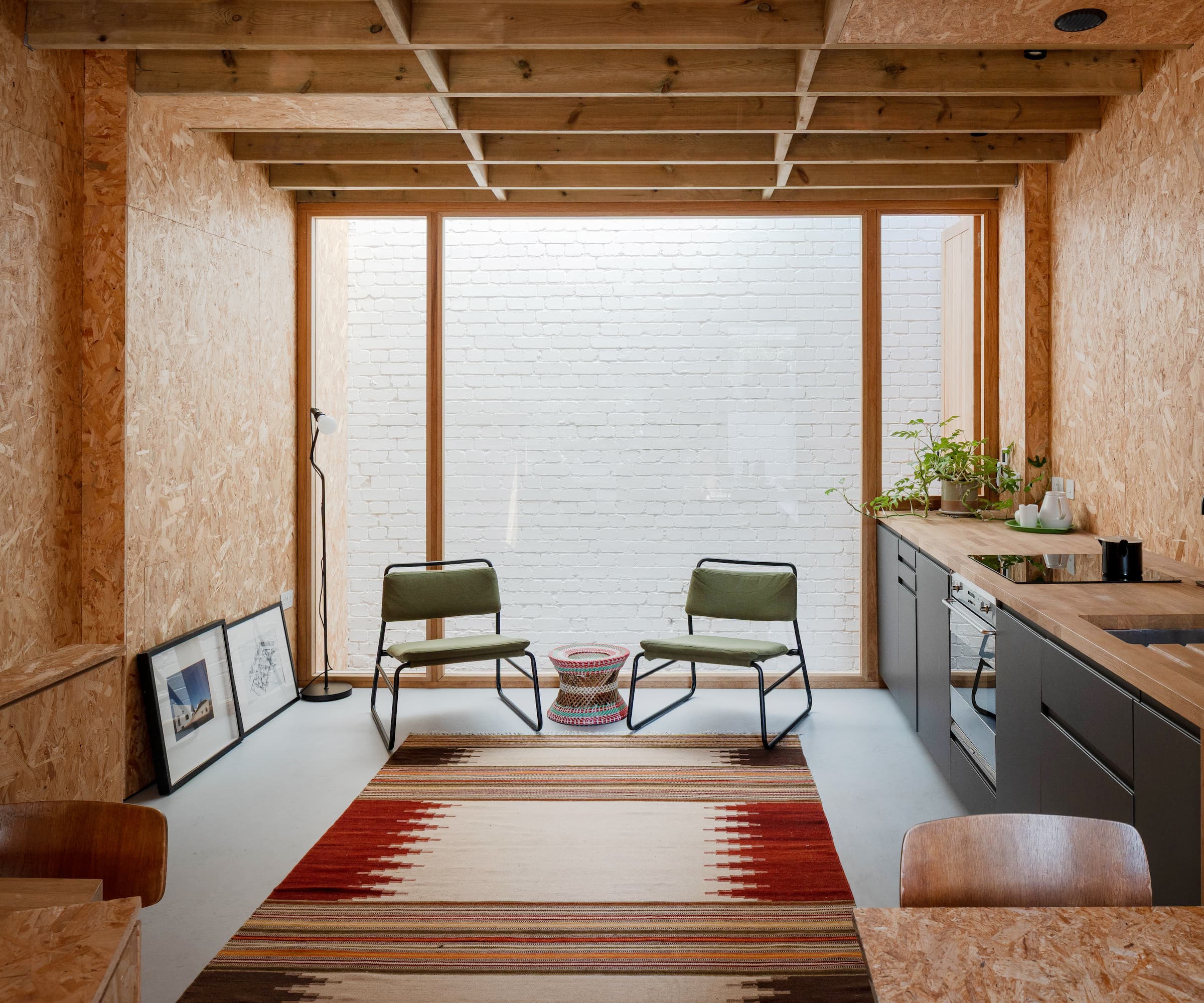 A kitchen-diner with plasterboard walls and a carpet on a cement layed floor