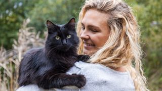 indoor to outdoor cat - woman holding a black cat outdoors