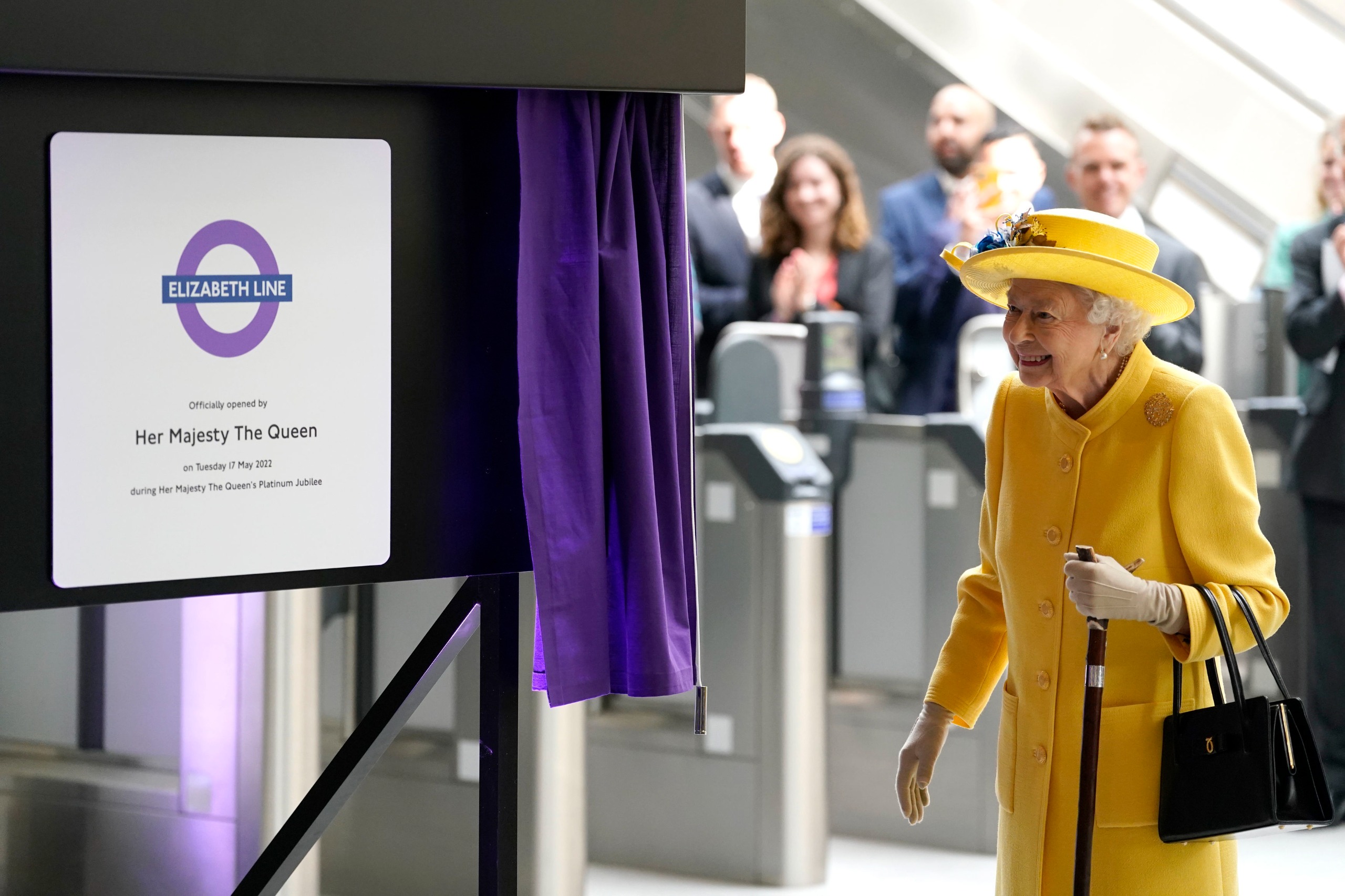Queen Elizabeth wearing a yellow coat and hat opening the Elizabeth line of the Underground