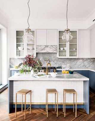 Blue and white kitchen with marble worktops and gold bar stools