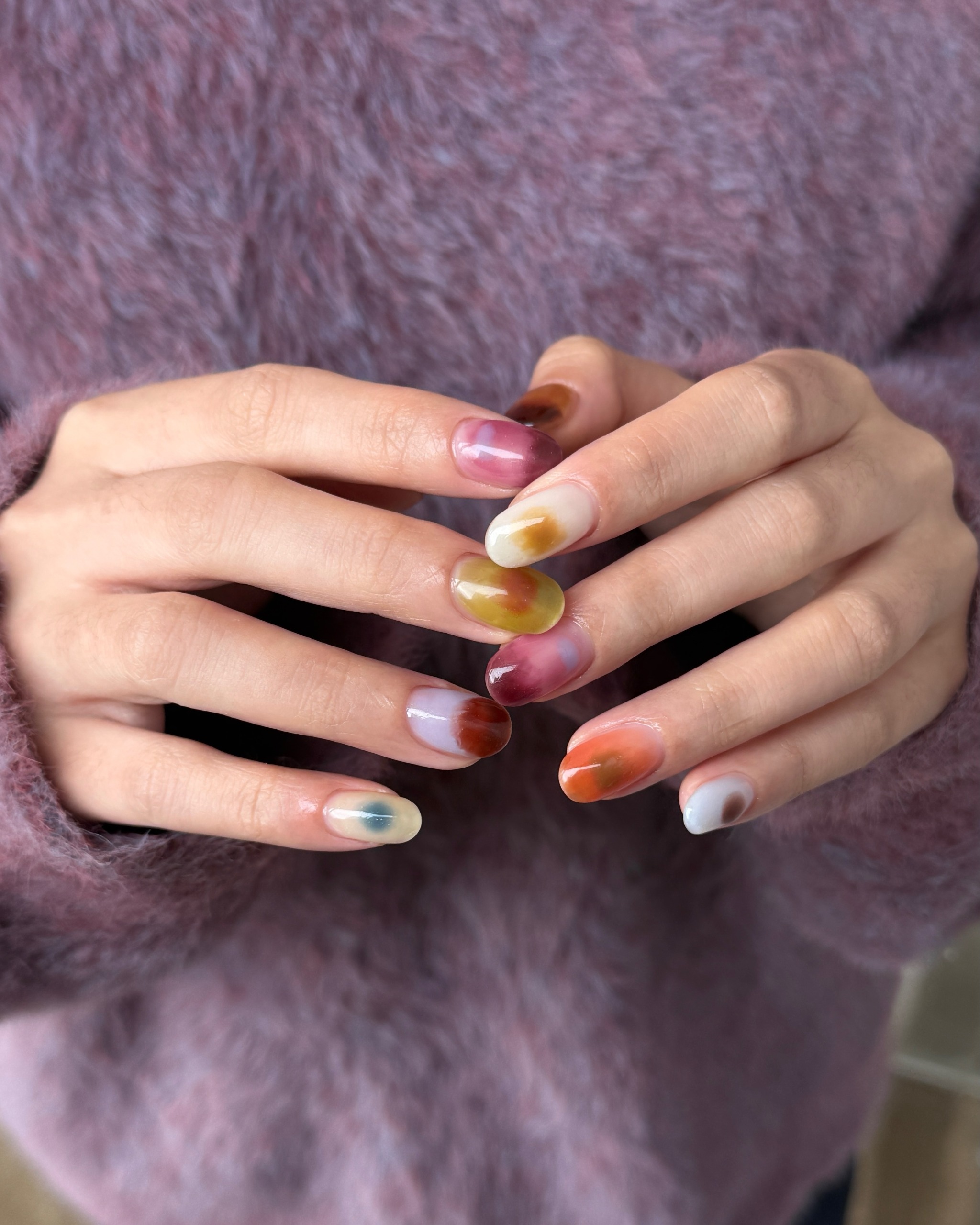 colorful jelly nails with blurry pink orange yellow and blue swirls on every finger