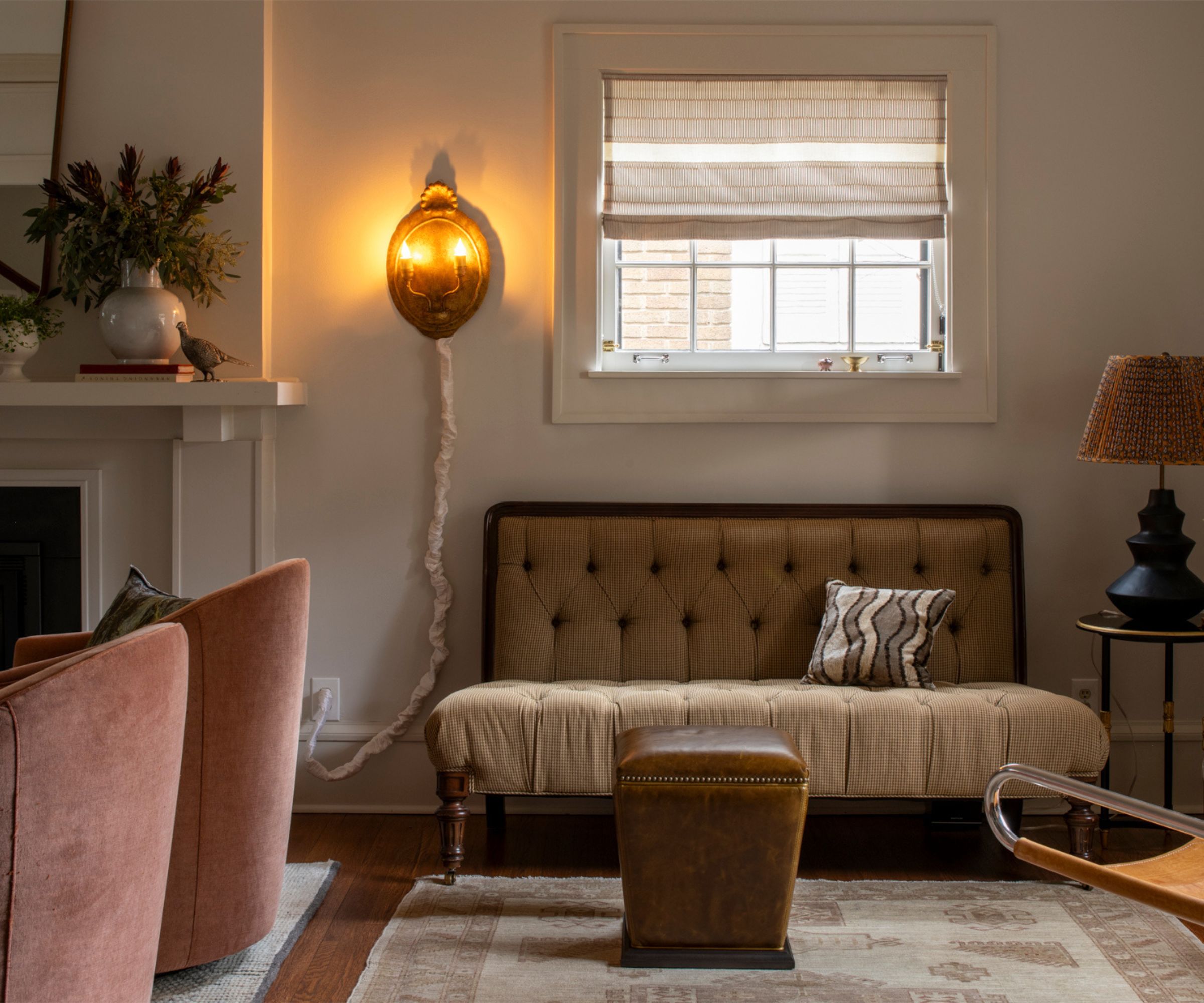 cozy living area next to a fireplace styled with a vintage rug, antique settee, side tables, and a candle style wall sconce