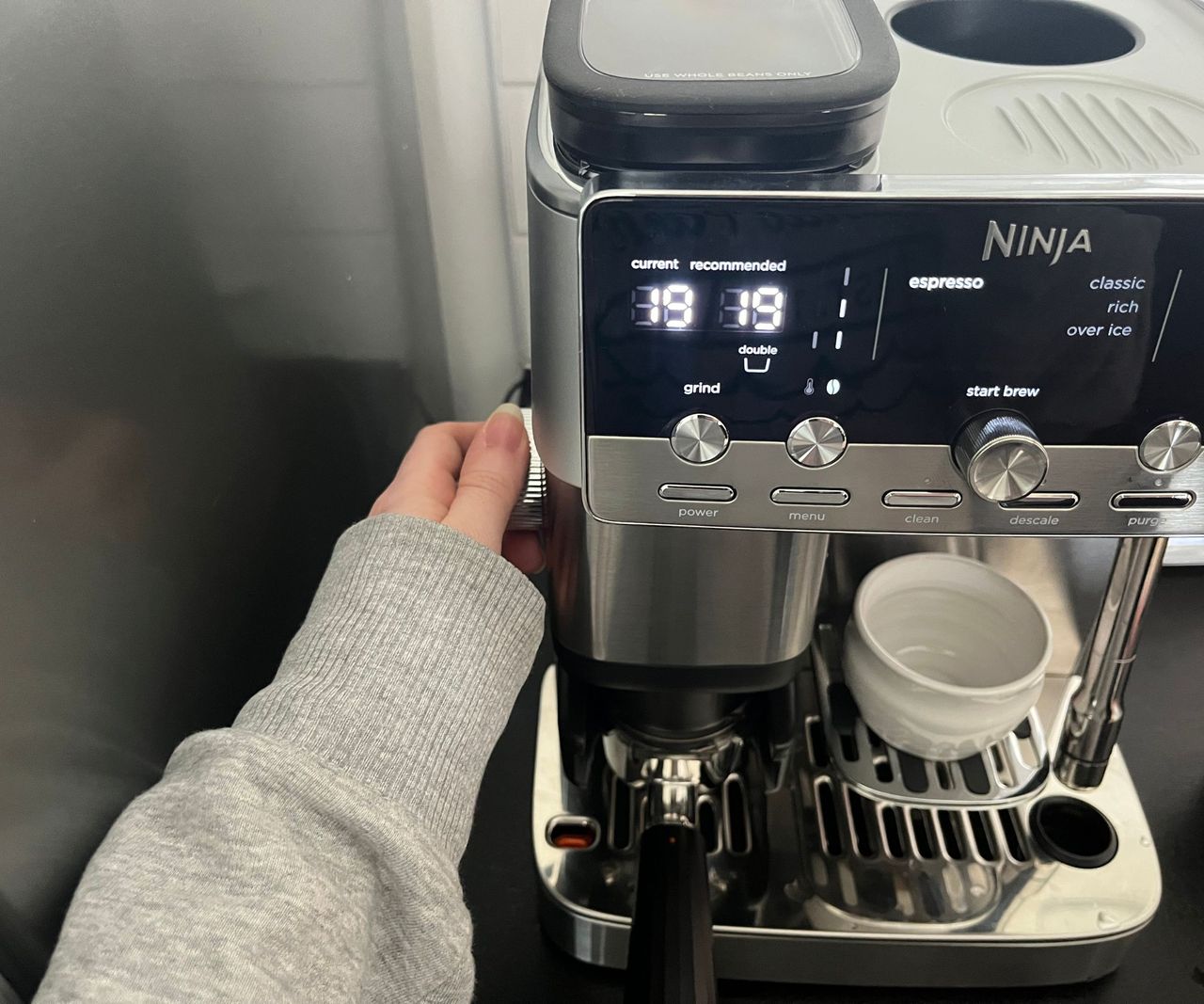 Adjusting the grind setting using a dial on the side of the Ninja Luxe caf&eacute; mini